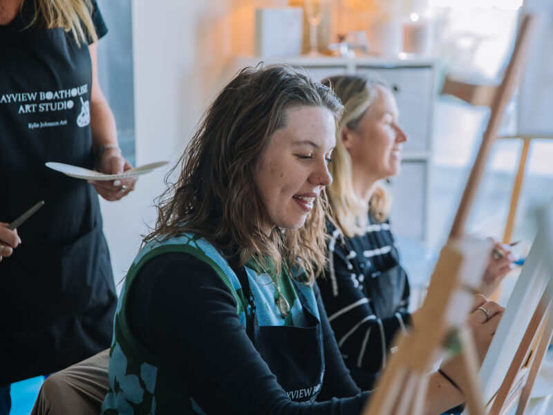 A woman painting at a paint and sip class.